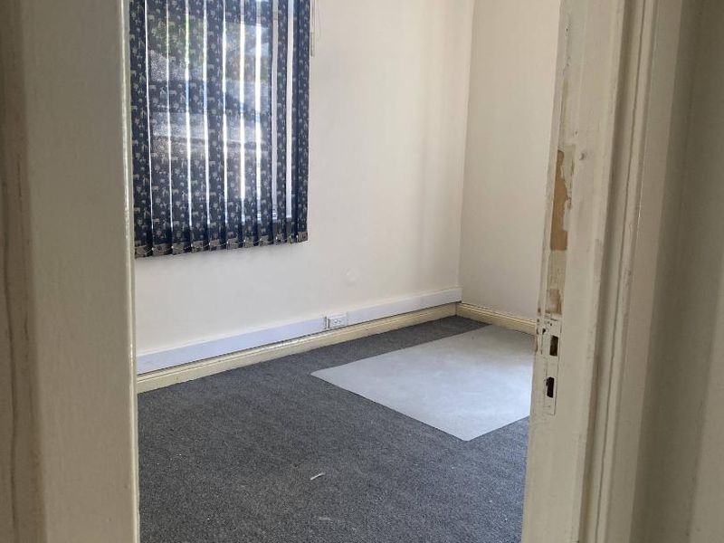 A vacant office space featuring grey carpeting, vertical window blinds, and perimeter electrical trunking, ready for professional fit-out.