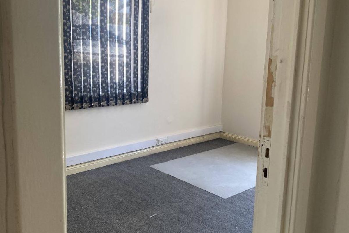 A vacant office space featuring grey carpeting, vertical window blinds, and perimeter electrical trunking, ready for professional fit-out.