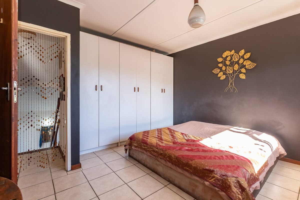 A bedroom featuring built-in white cabinetry, tiled flooring, and a dark accent wall.