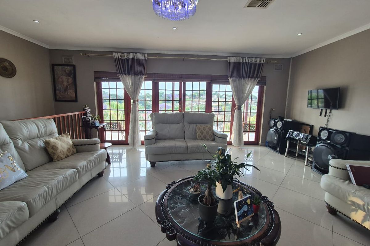 Spacious living room featuring large wooden-framed glass doors, polished tiled flooring, and recessed ceiling lighting with an integrated air conditioning system.
