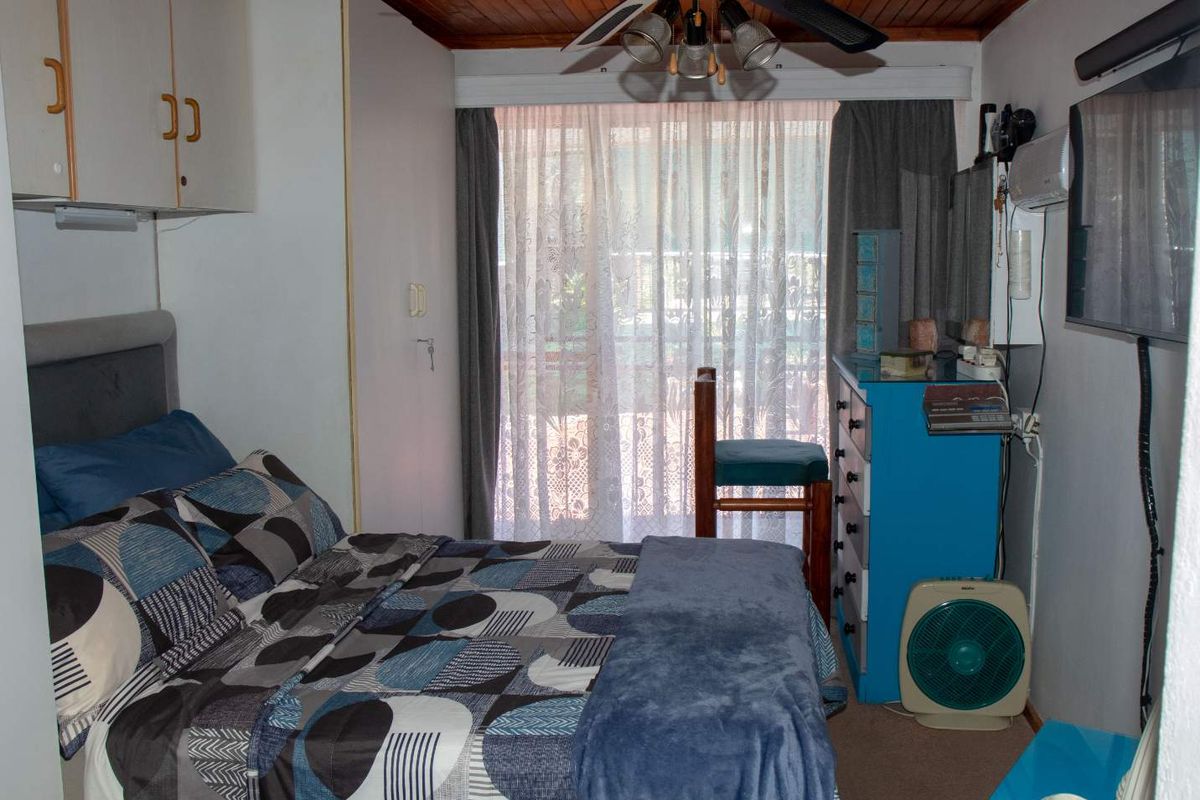 A bedroom featuring a timber-paneled ceiling, built-in cabinetry, and sliding glass doors providing access to an outdoor area.