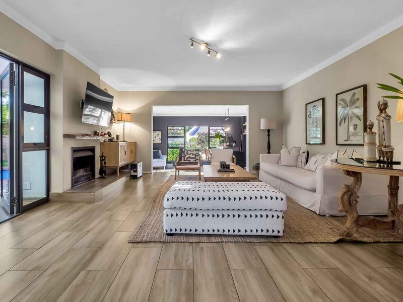 Spacious living room featuring tiled flooring, a fireplace with a stone hearth and timber mantel, and large sliding glass doors leading to the patio.