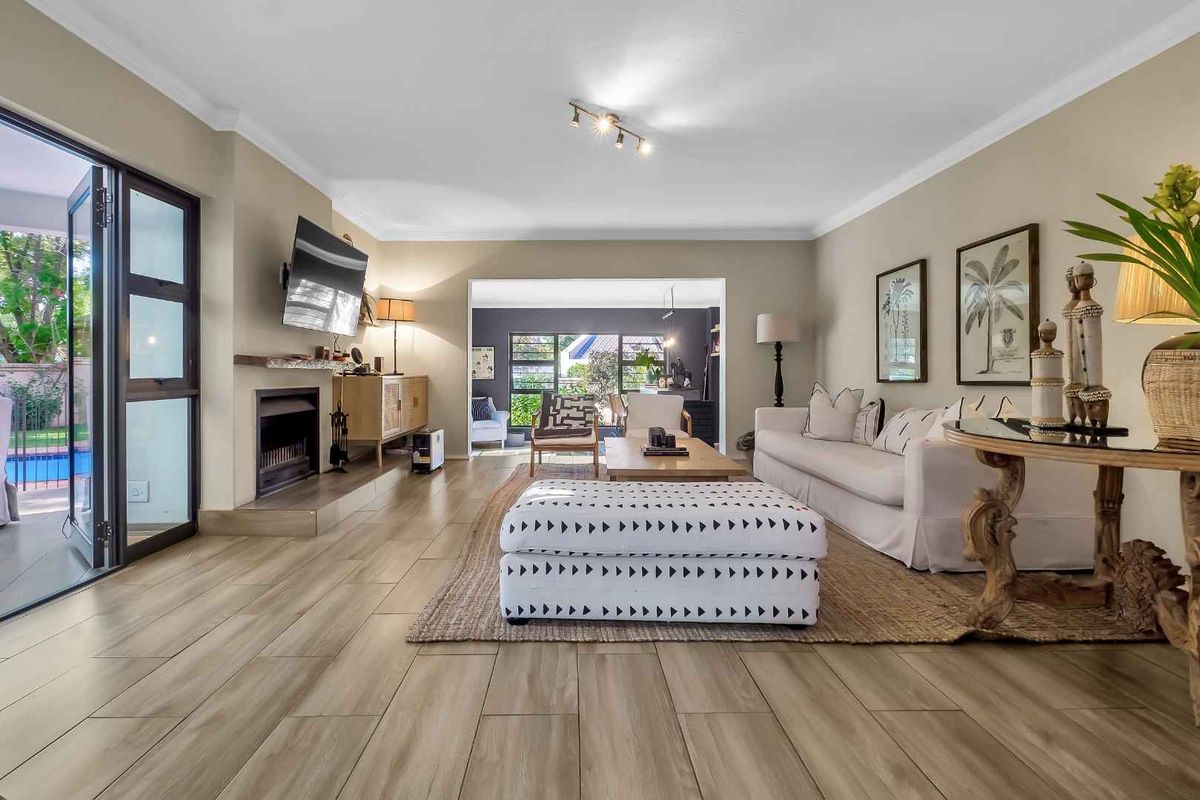 Spacious living room featuring tiled flooring, a fireplace with a stone hearth and timber mantel, and large sliding glass doors leading to the patio.