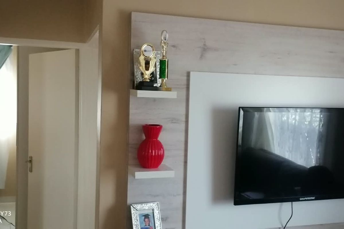A living room featuring a modern, light-wood finish built-in media wall unit with integrated floating shelving.