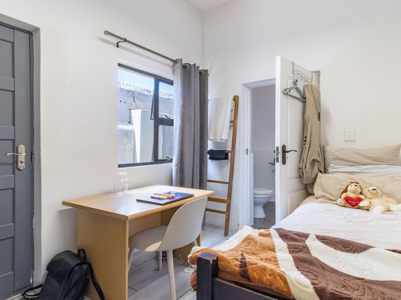 A functional bedroom featuring tiled flooring, an aluminium window, and direct access to an en-suite bathroom.
