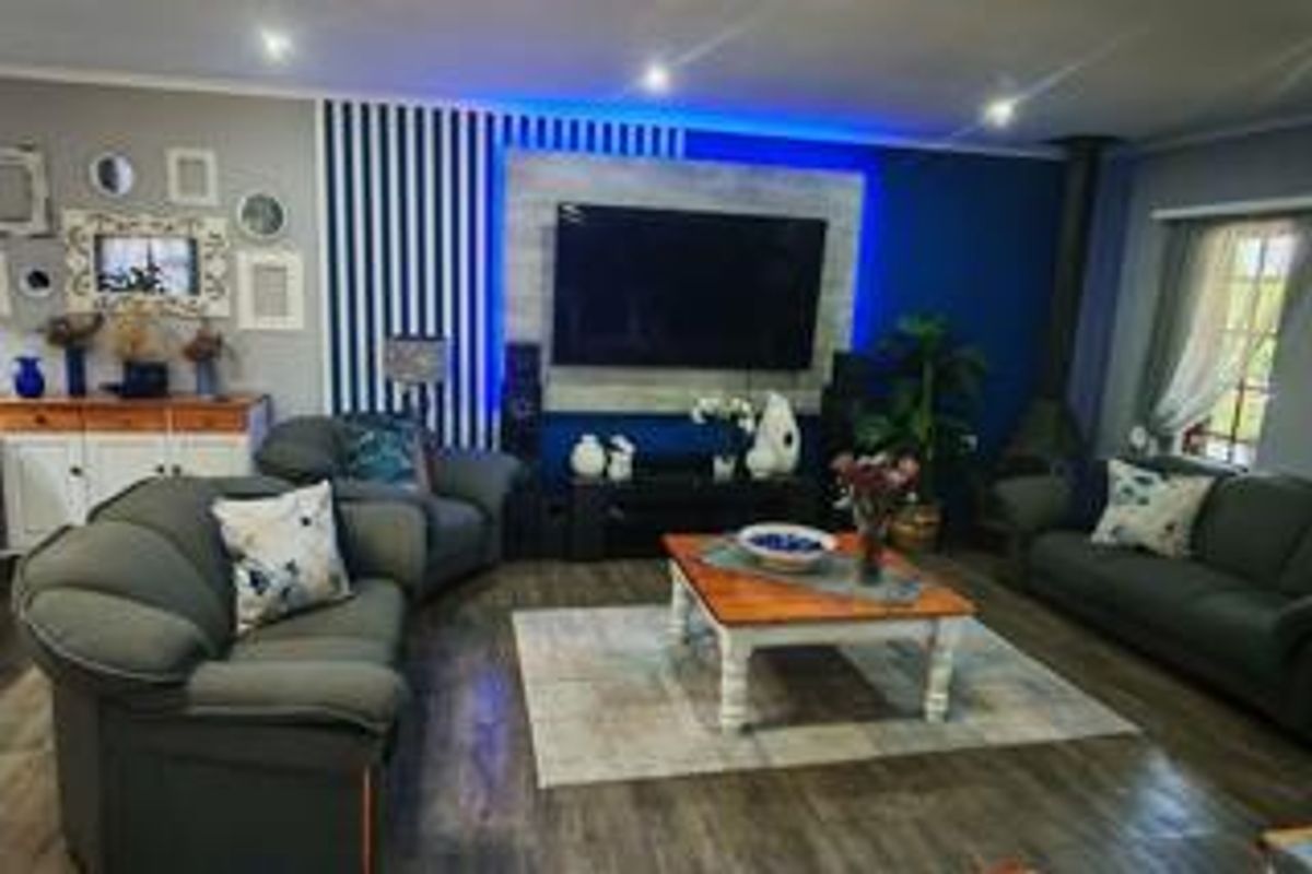 Spacious living room featuring a modern feature wall with integrated LED lighting and a built-in fireplace, finished with wood-look flooring.