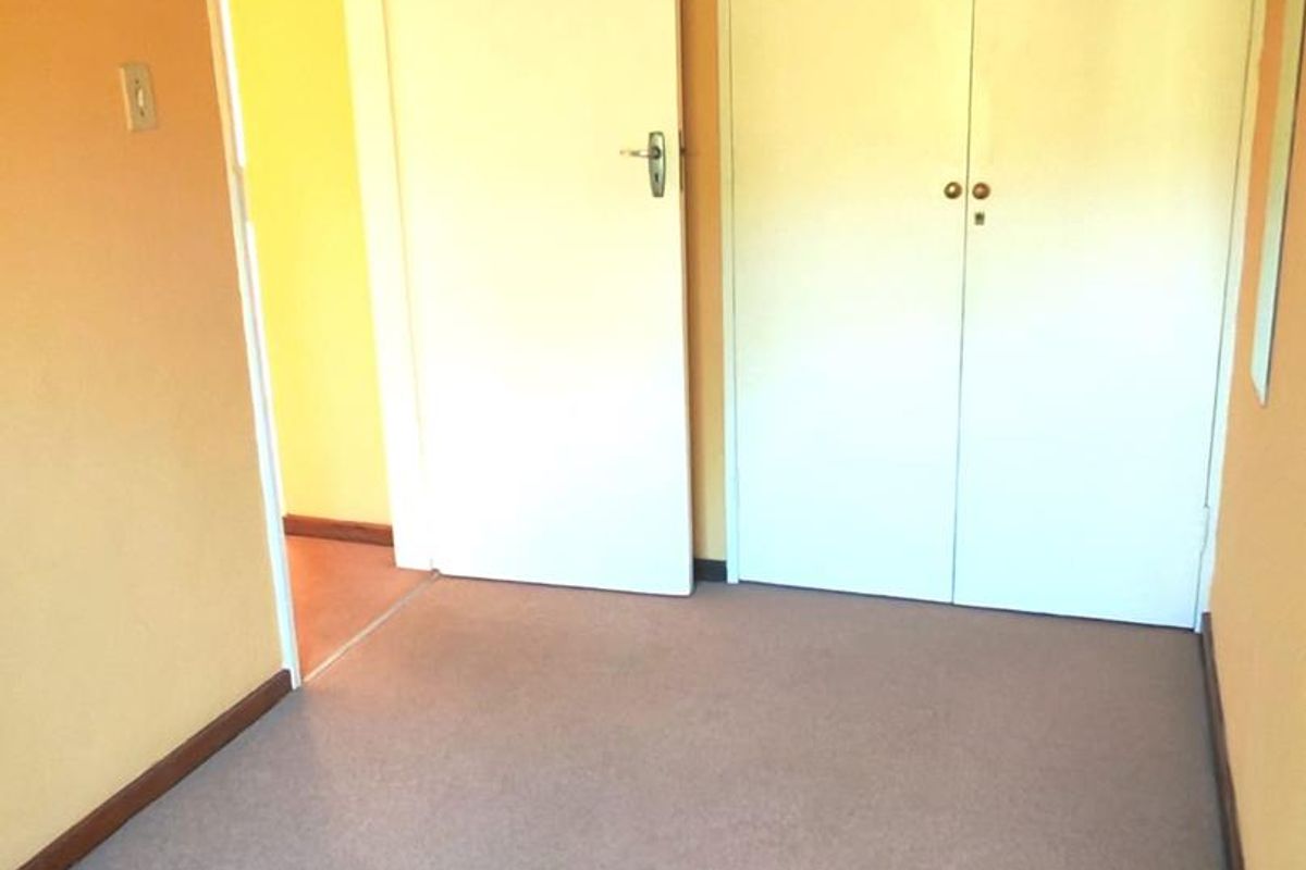 An empty bedroom featuring built-in cupboards and carpeted flooring, presenting a blank canvas for potential updates and interior design improvements.