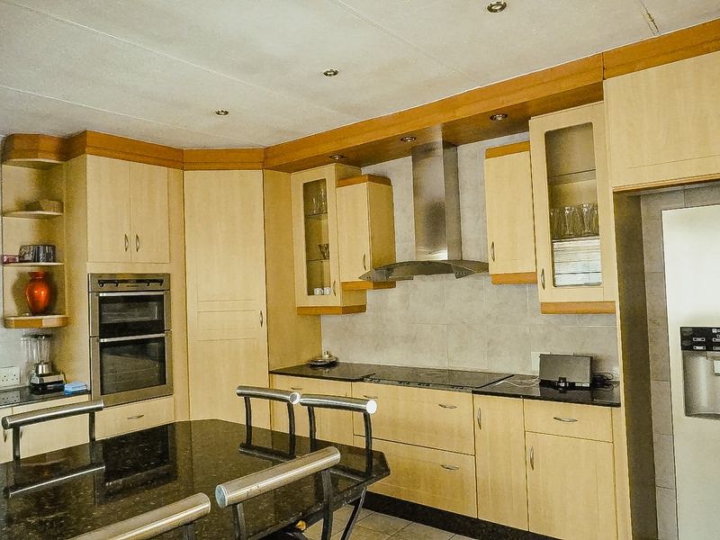 A functional kitchen featuring light wood cabinetry, granite countertops, a built-in double oven, and a stainless steel extractor fan.