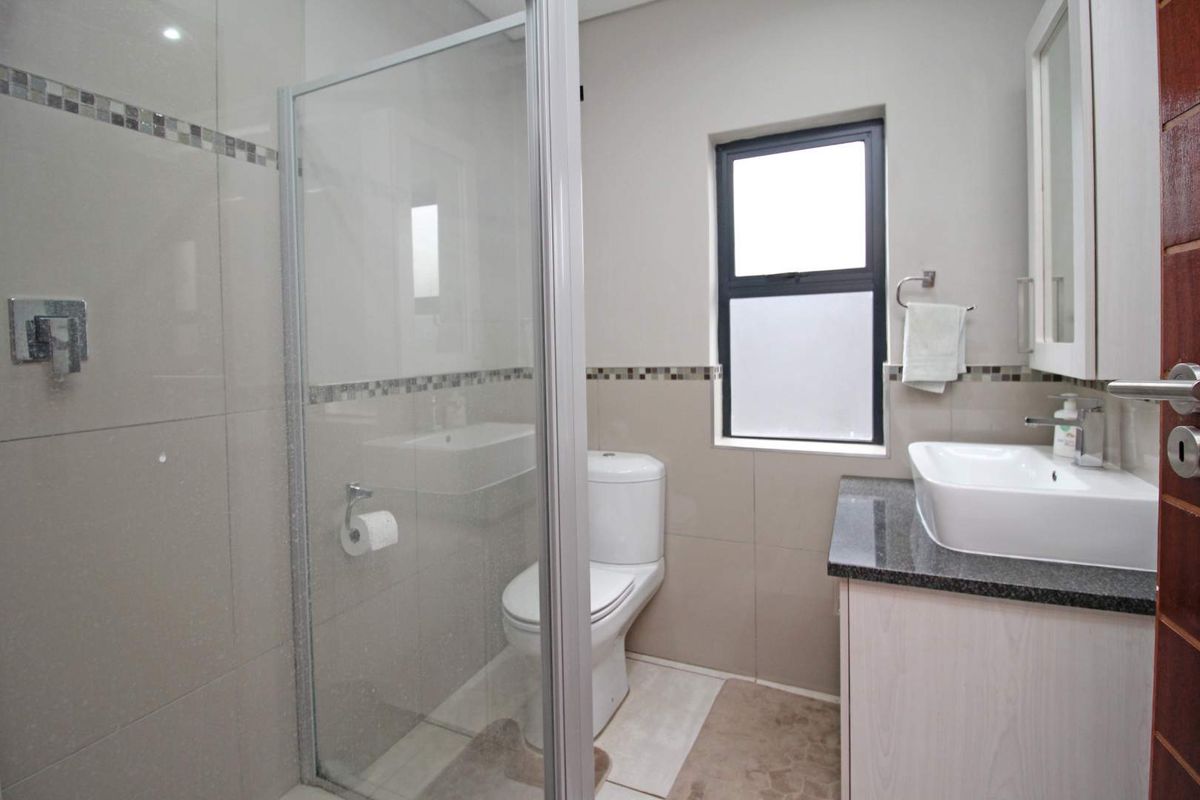 A modern bathroom featuring a glass-enclosed shower, a vanity with a granite countertop, a vessel sink, and a toilet.