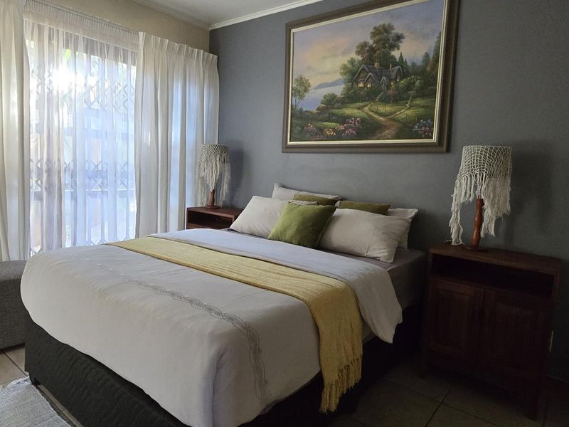 A well-lit bedroom featuring tiled flooring and a sliding glass door with security gate, providing access to the exterior.