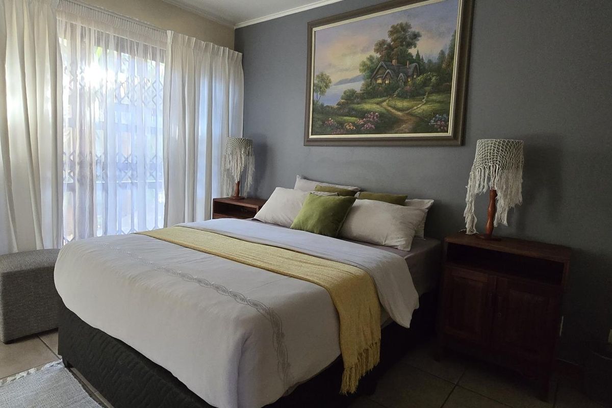 A well-lit bedroom featuring tiled flooring and a sliding glass door with security gate, providing access to the exterior.
