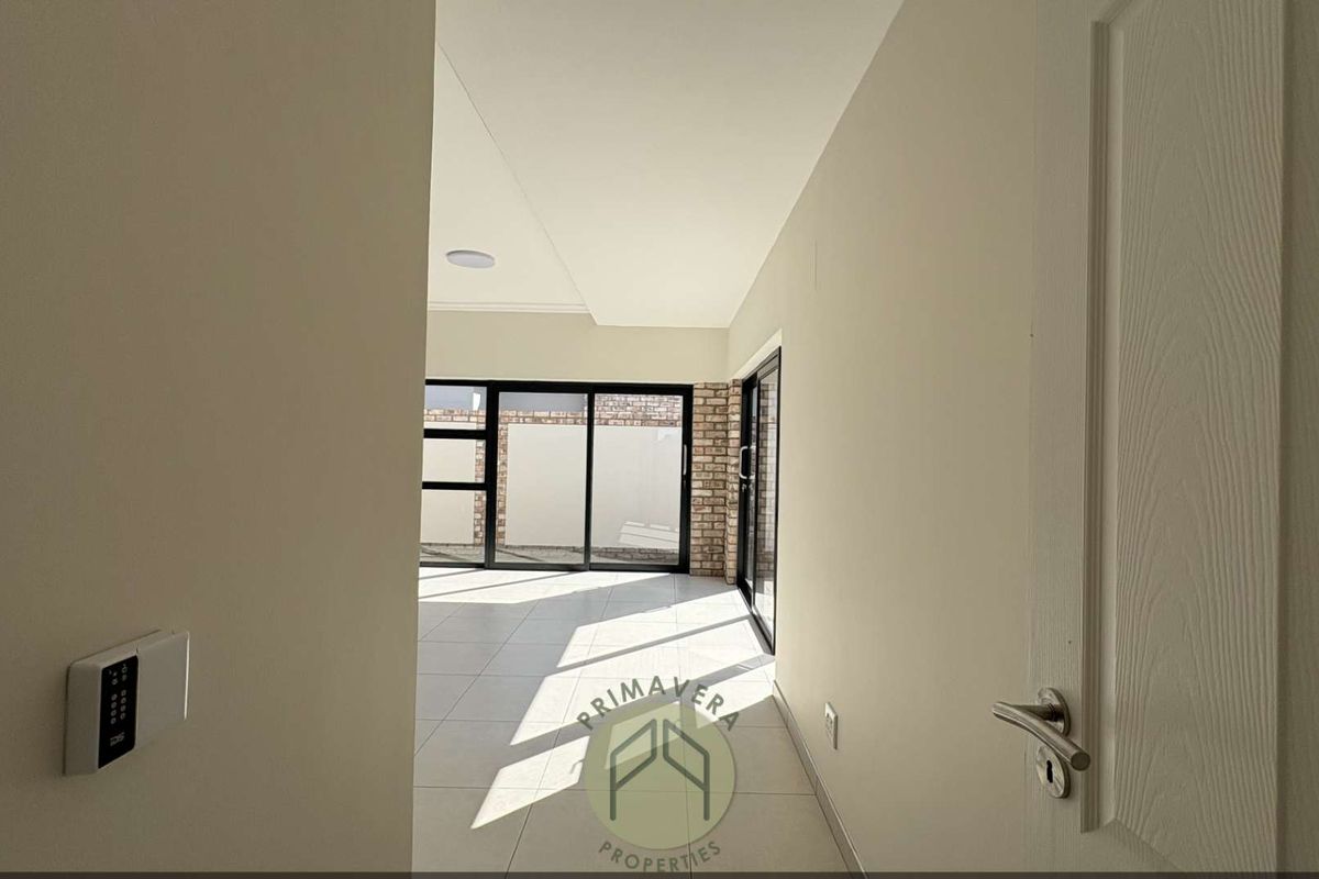 Bright and spacious living area featuring neutral tiled flooring, recessed lighting, and large sliding glass doors leading to an outdoor space.