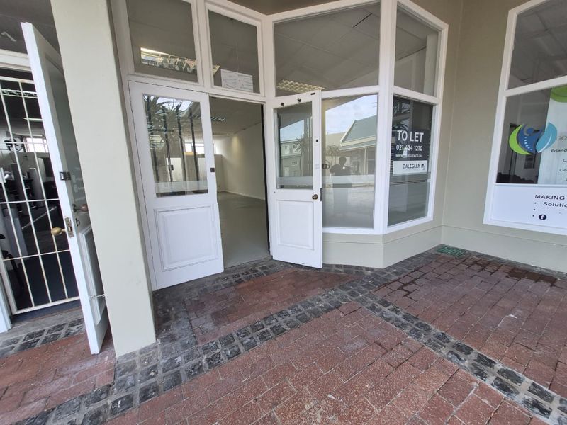 Front entrance of a retail space featuring a glass storefront, double doors, and paved walkway access.
