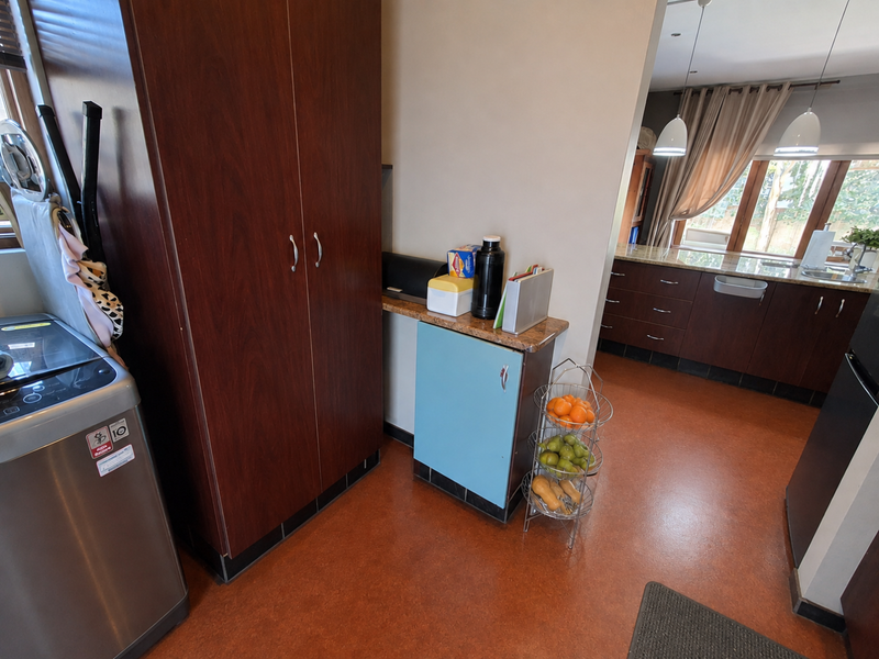 A functional kitchen area featuring dark wood cabinetry, laminate countertops, and durable flooring, with an open-plan layout connecting to the adjacent living space.
