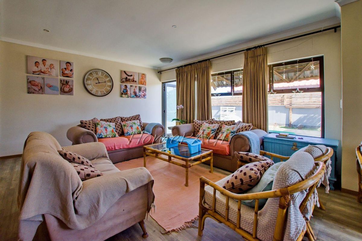 A comfortable living room featuring large windows with curtains, providing natural light and access to the outdoor area.