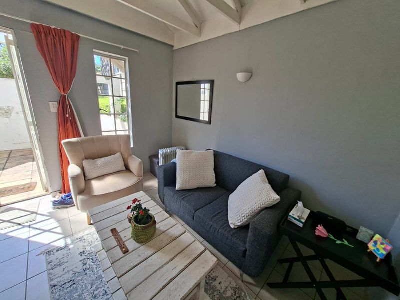 A cozy living room featuring exposed timber rafters, tiled flooring, and direct access to an outdoor patio area.