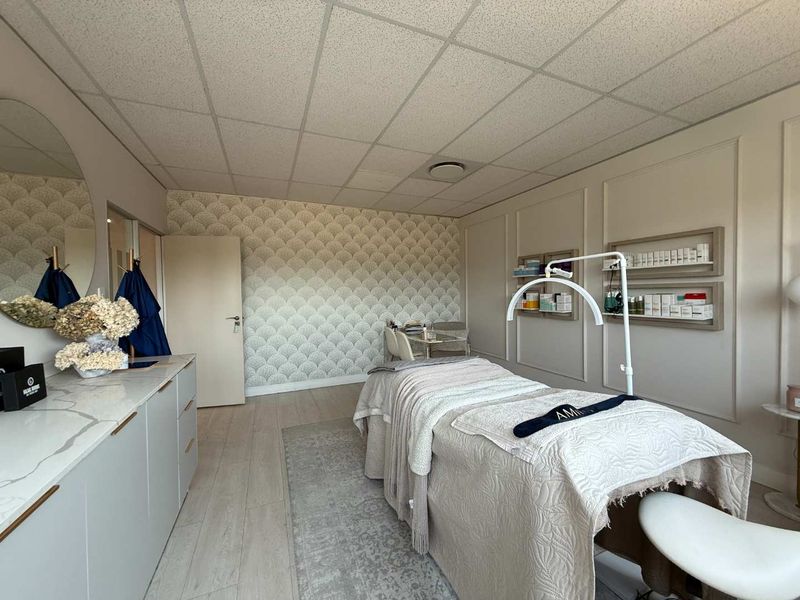 A well-maintained office or treatment room featuring built-in cabinetry with stone countertops, decorative wall paneling, and acoustic ceiling tiles.