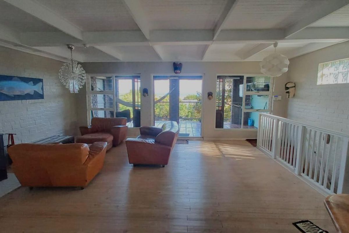 Spacious living area featuring a wood-burning fireplace, exposed beam ceiling, and large glass sliding doors opening onto an outdoor balcony.