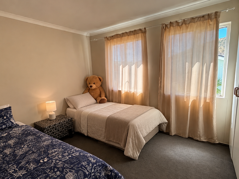 A functional bedroom featuring neutral wall tones, carpeted flooring, and a built-in wardrobe with wooden handles.