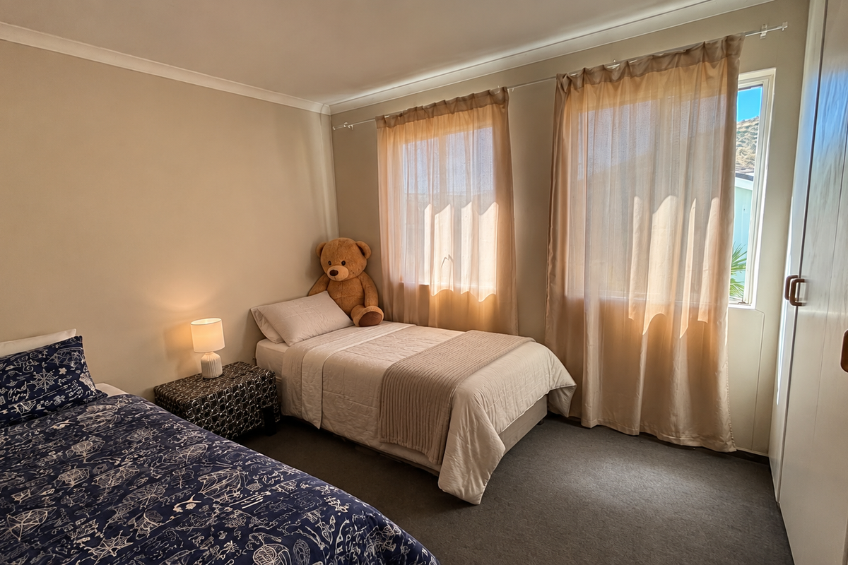 A functional bedroom featuring neutral wall tones, carpeted flooring, and a built-in wardrobe with wooden handles.