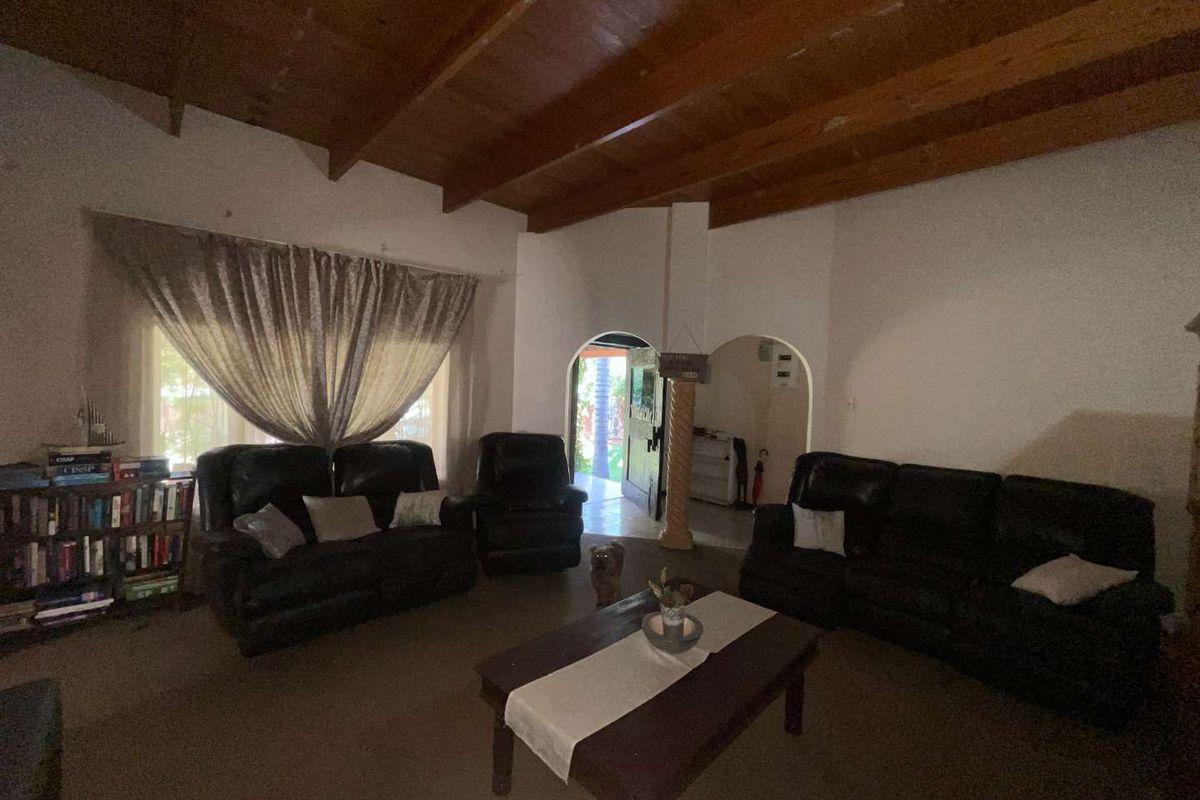 Spacious living room featuring high vaulted timber ceilings and arched doorways leading to an adjacent area.