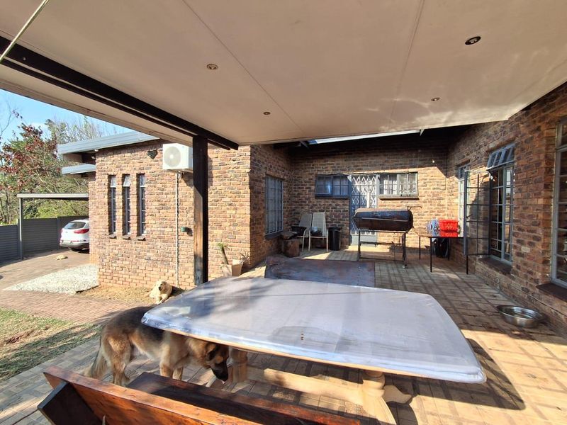 A spacious covered patio area featuring exposed brickwork, paved flooring, and recessed lighting, providing a functional outdoor entertainment space.