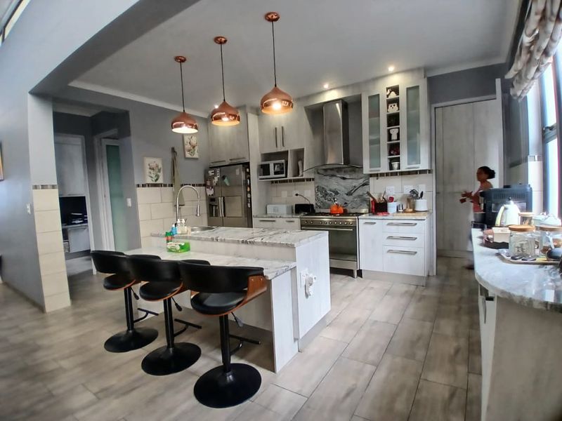 Modern kitchen featuring a central island with stone countertops, pendant lighting, built-in cabinetry, and high-quality stainless steel appliances.