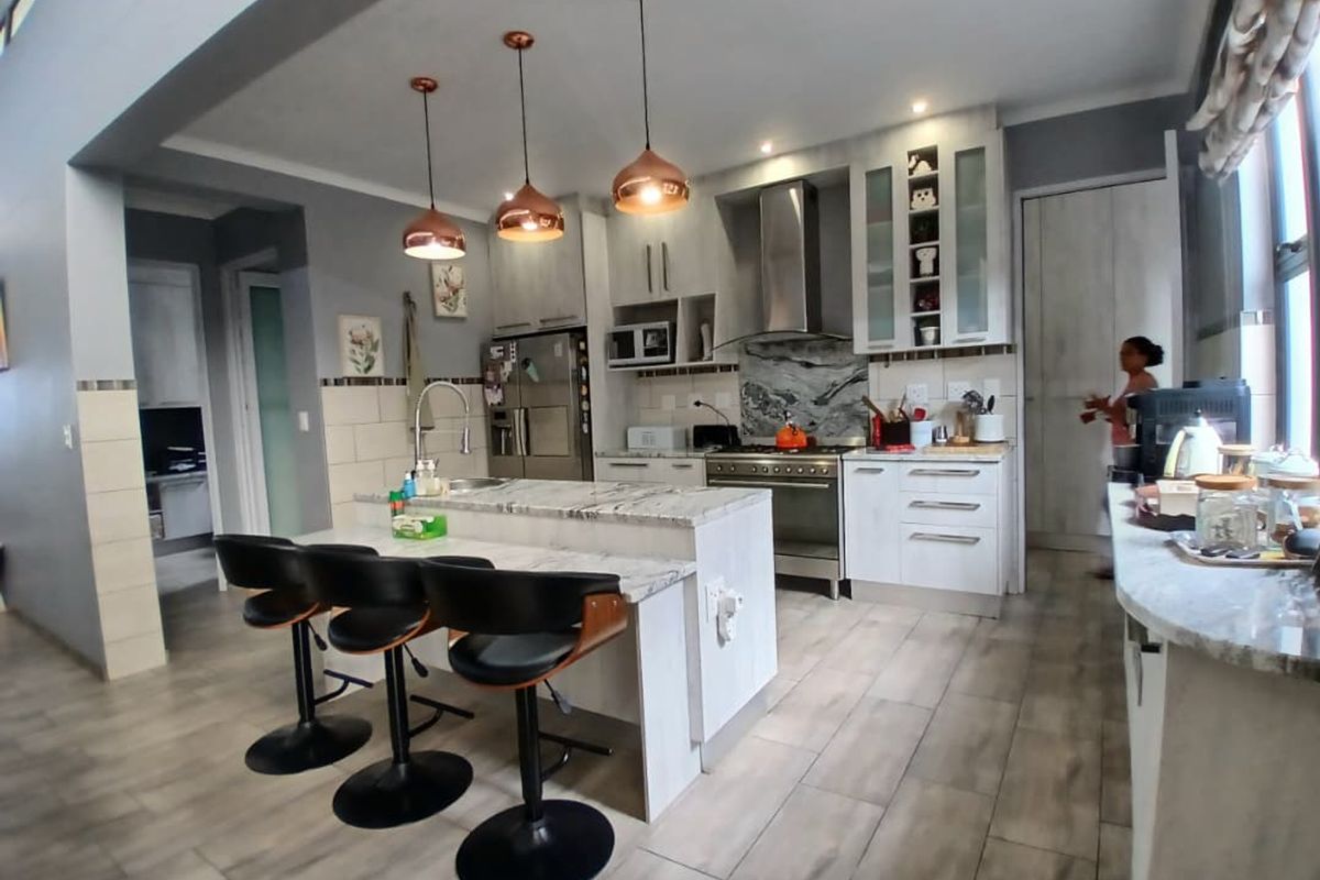 Modern kitchen featuring a central island with stone countertops, pendant lighting, built-in cabinetry, and high-quality stainless steel appliances.