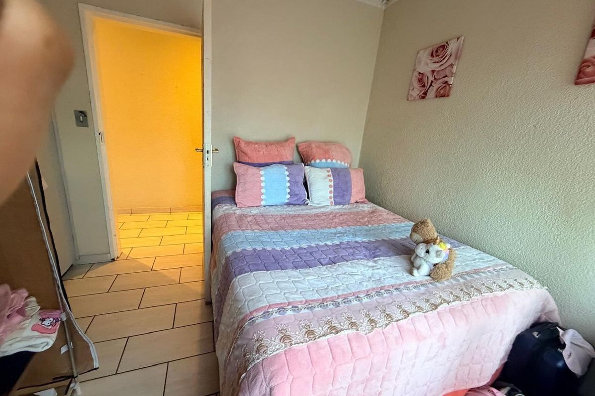 A compact bedroom featuring tiled flooring and a standard doorway leading to an adjacent space.