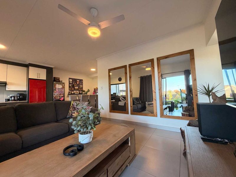 An open-plan living and kitchen area featuring tiled flooring, a ceiling fan, and modern cabinetry, creating a functional and connected living space.