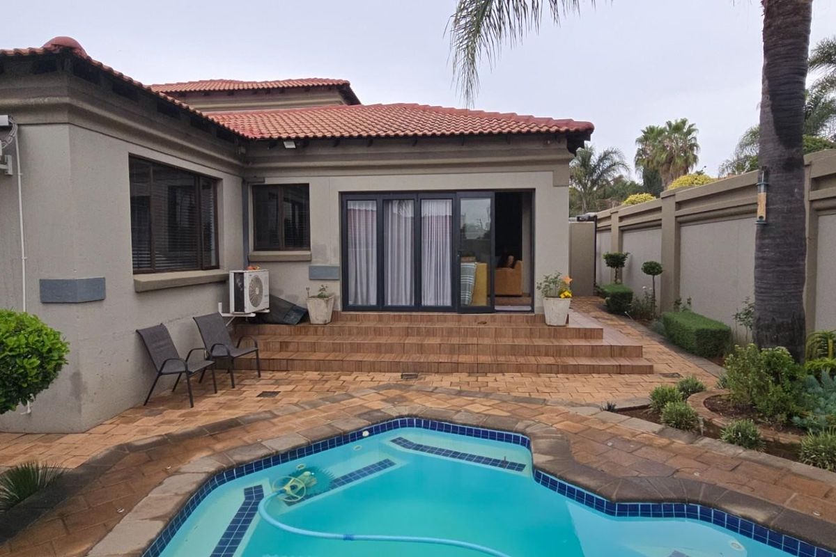 Rear exterior view featuring a swimming pool, paved patio area, and direct access to the home through sliding glass doors.