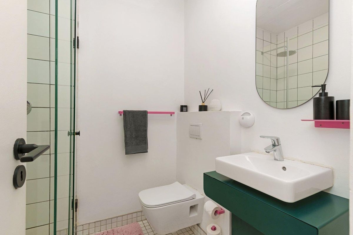 A modern bathroom featuring a wall-mounted toilet, a glass shower enclosure, and a vanity basin with contemporary fixtures.