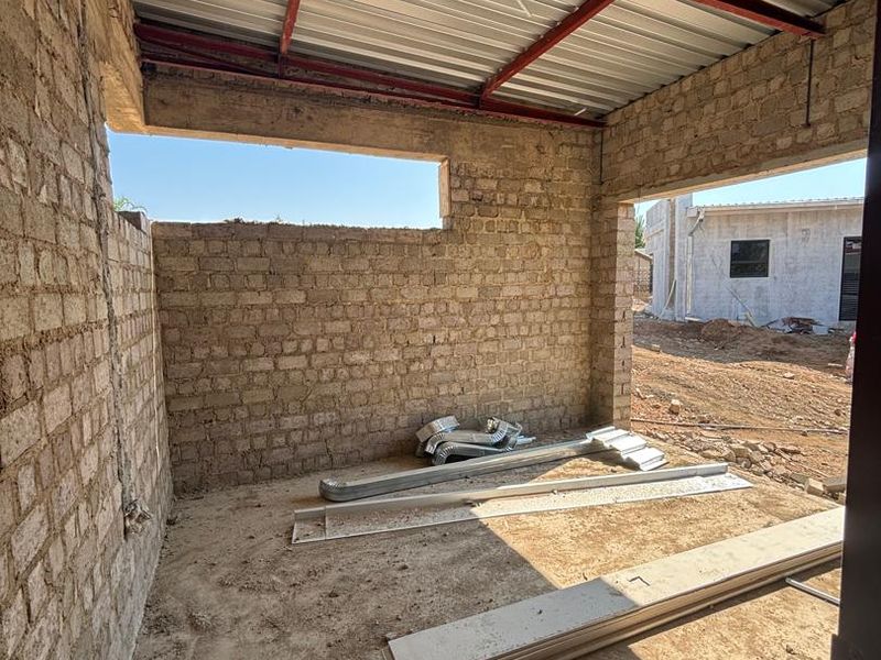 An unfinished utility space or construction area featuring exposed brick walls, a corrugated metal roof, and a concrete floor.