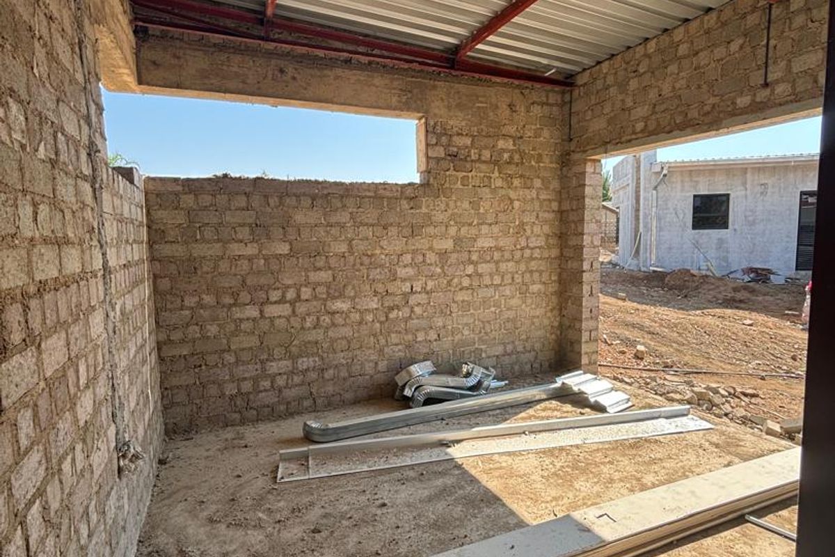 An unfinished utility space or construction area featuring exposed brick walls, a corrugated metal roof, and a concrete floor.