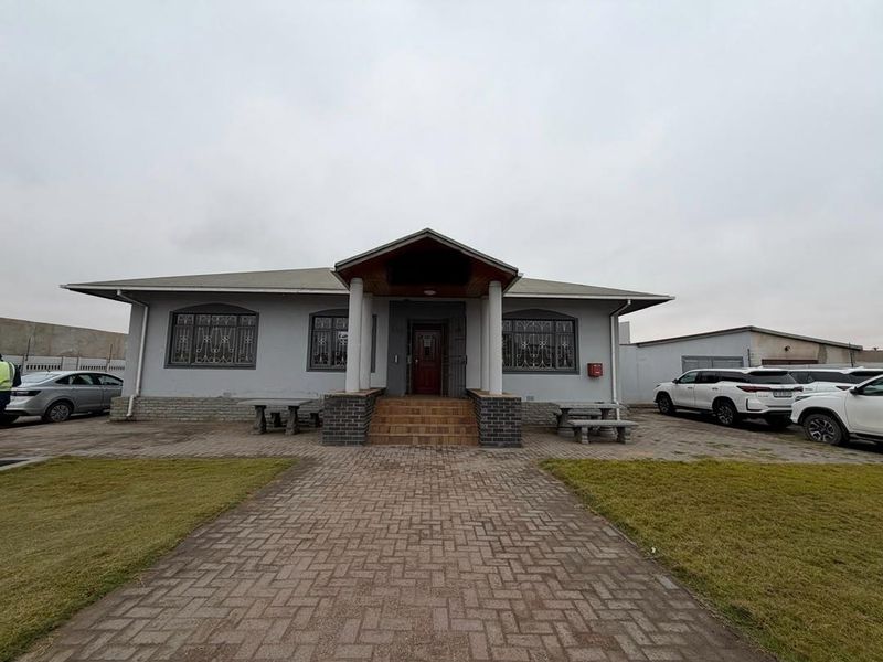 Front elevation of a single-story office building featuring a paved driveway, covered entrance porch, and secure window treatments.