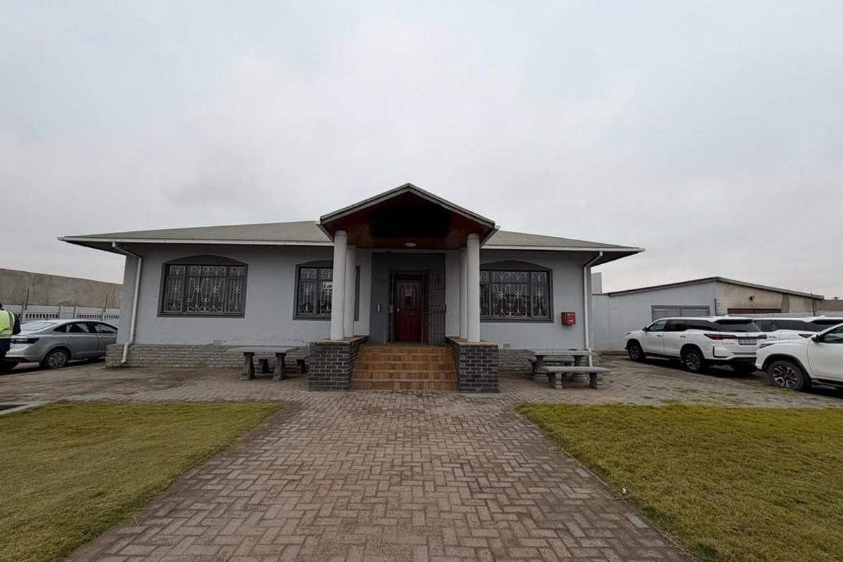 Front elevation of a single-story office building featuring a paved driveway, covered entrance porch, and secure window treatments.