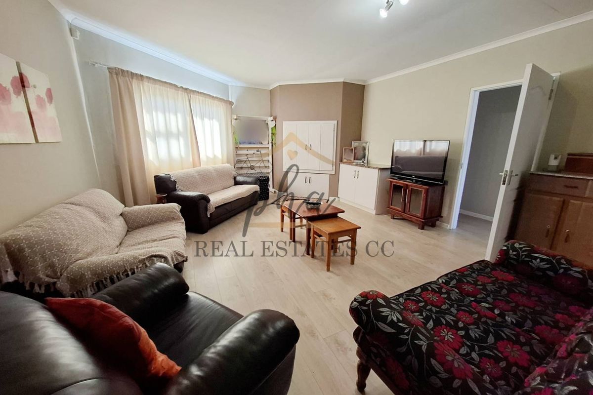 A spacious living room featuring light-toned laminate flooring, built-in cabinetry, and neutral wall finishes, providing a comfortable and functional family living space.