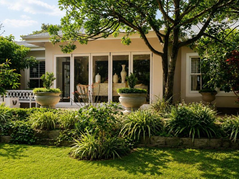 A well-maintained rear exterior view featuring a landscaped garden, stone retaining wall, and large bi-fold doors leading into the home.