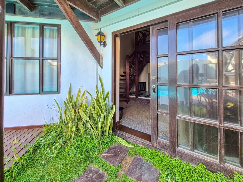 A covered patio area featuring timber sliding doors, decking, and a pergola, providing direct access to the interior living space.