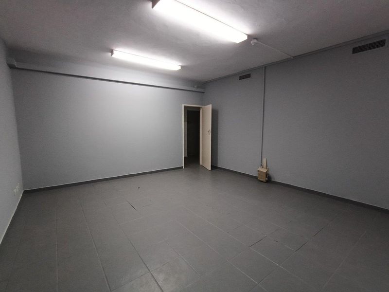 A clean, empty utility or storage space featuring tiled flooring, fluorescent strip lighting, and integrated ventilation ducts.