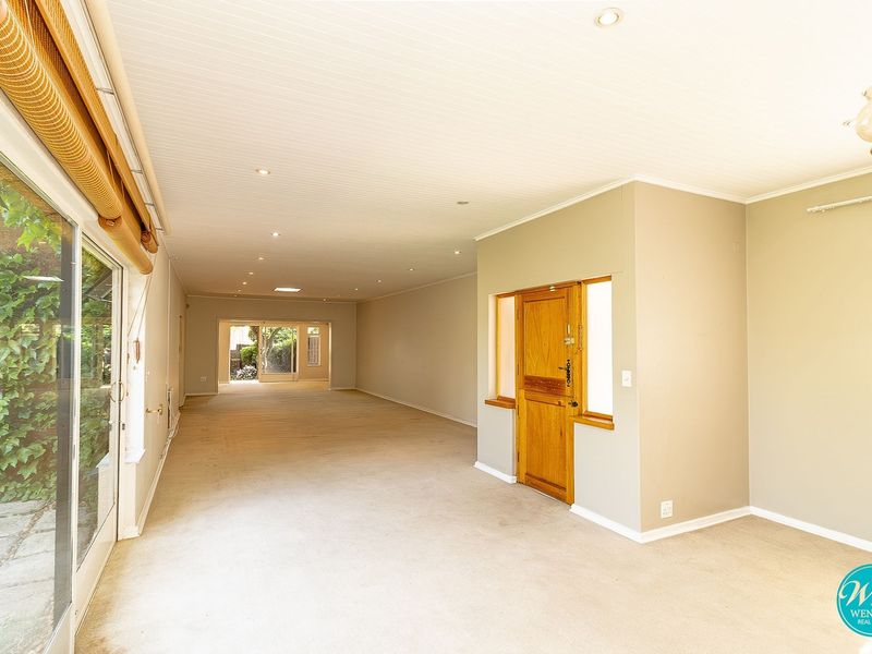 Spacious, light-filled open plan living area featuring neutral carpeting, recessed lighting, and large sliding glass doors providing access to the exterior.