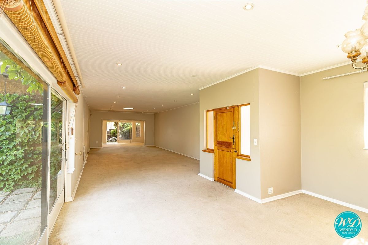 Spacious, light-filled open plan living area featuring neutral carpeting, recessed lighting, and large sliding glass doors providing access to the exterior.