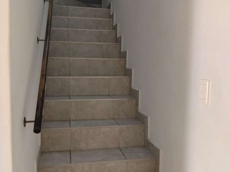 A functional staircase featuring tiled steps and a wooden handrail, providing access between levels in the townhouse.