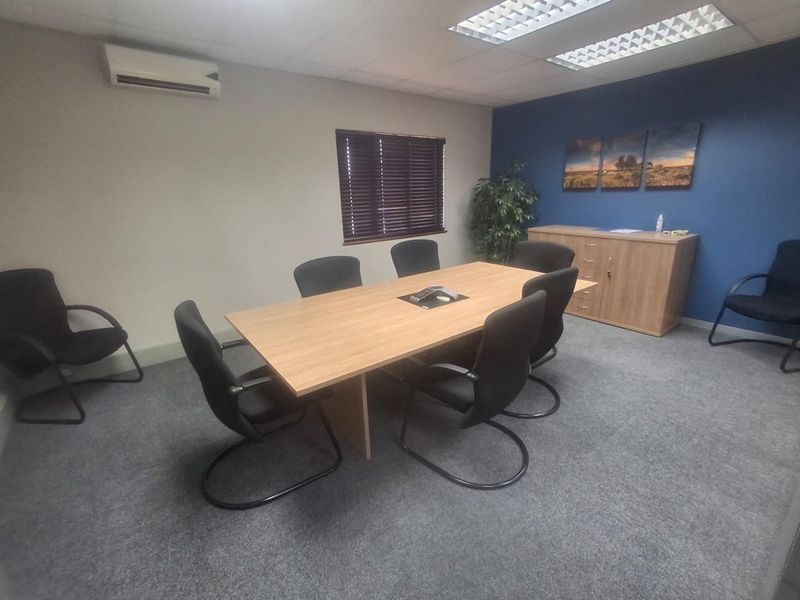A functional office meeting room featuring carpeted flooring, recessed lighting, a split-system air conditioner, and a built-in storage cabinet.