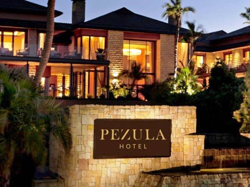 A view of the Pezula Hotel entrance featuring stone masonry, a water feature, and illuminated architectural elements.