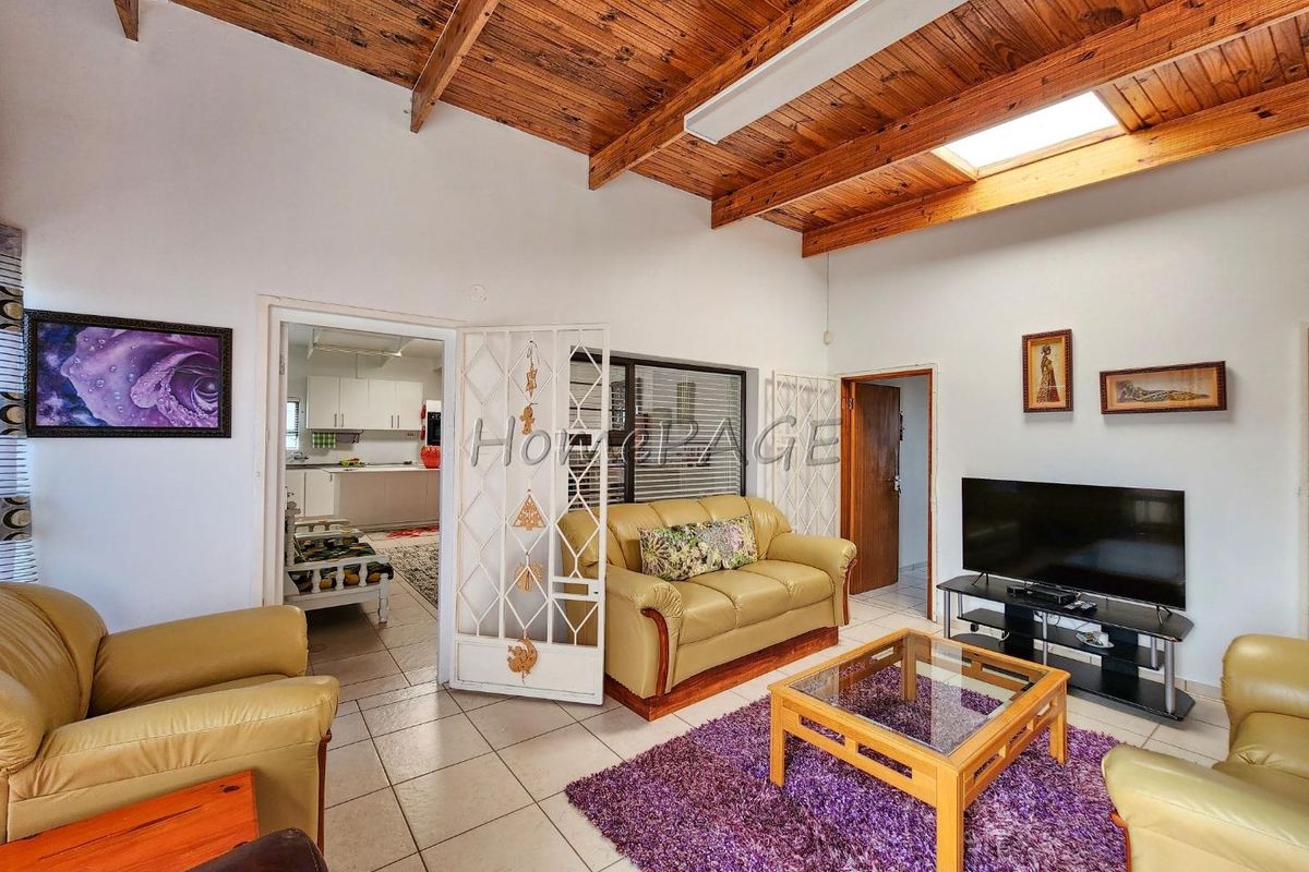 Spacious living room featuring a high vaulted timber-clad ceiling with a skylight, tiled flooring, and direct access to the kitchen area.