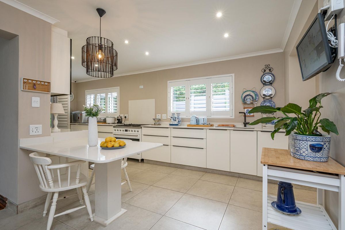 Modern kitchen featuring white cabinetry, stone countertops, integrated gas stove, and tiled flooring with plantation shutters.