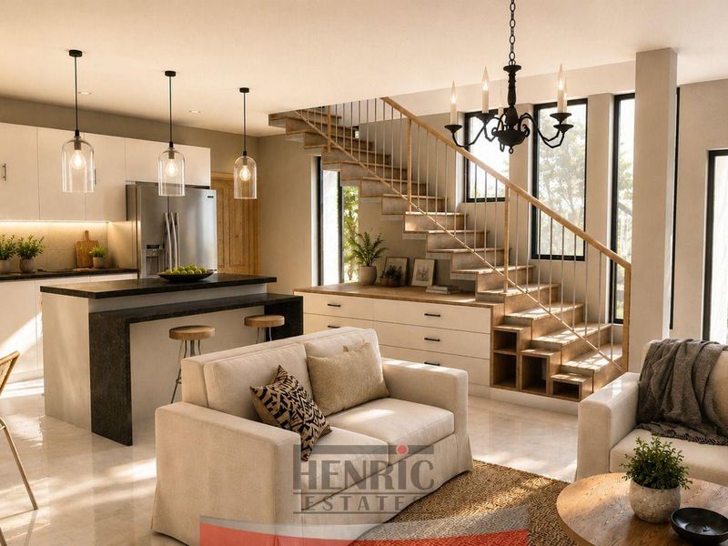Modern open-plan living area featuring a sleek kitchen with island, integrated staircase with built-in storage, and large glass doors leading to the exterior.