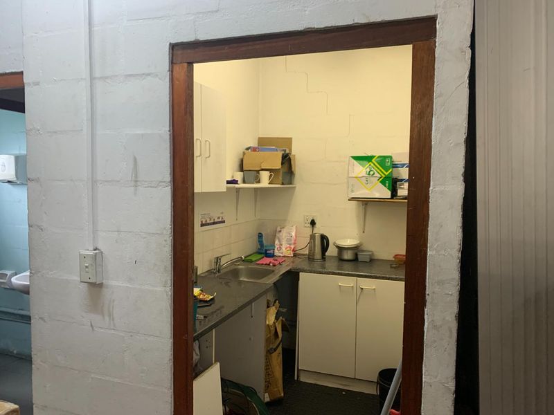 A compact scullery or kitchenette area featuring built-in cabinetry, a stainless steel sink, and tiled splashback, requiring cosmetic updates to improve the finish.