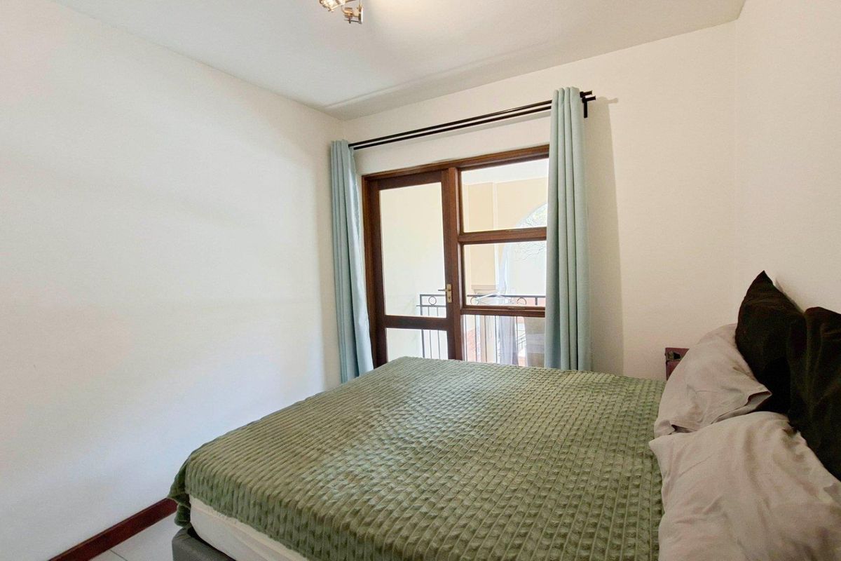 A bedroom featuring a wooden door with glass panels leading to a balcony, providing natural light and access to outdoor space.